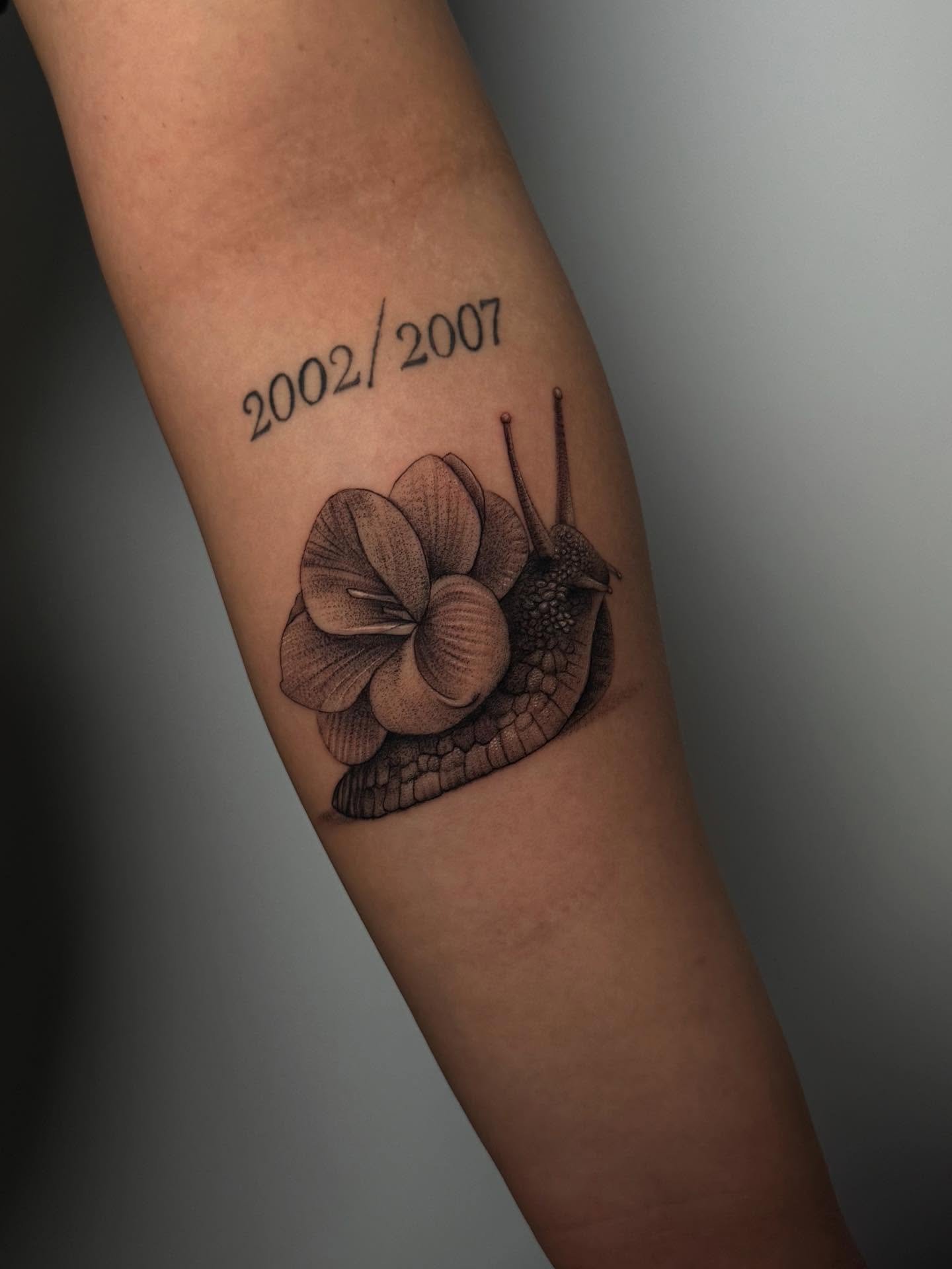 Snail and flower dotwork tattoo on the forearm by Stephanie Pedraza