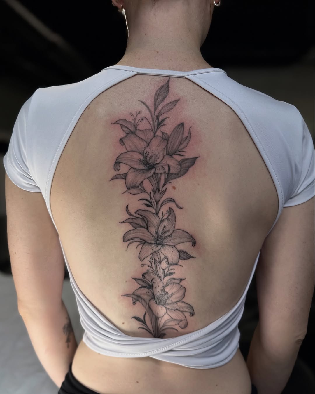 Lilies on spine fine line tattoo on the back by IVY
