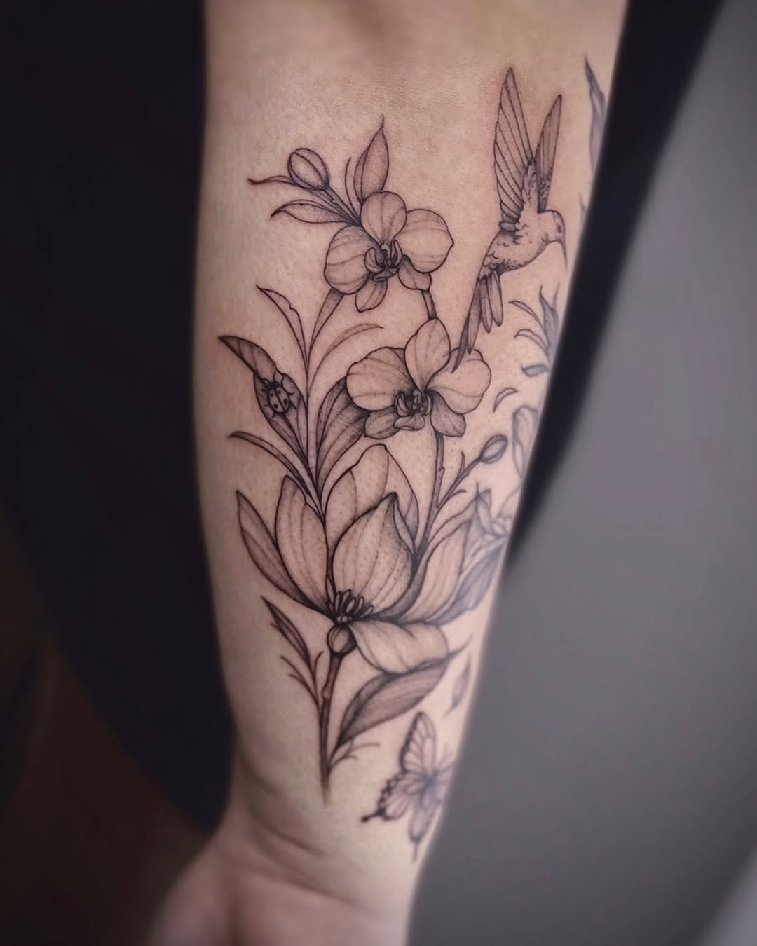 Hummingbird and orchids fine line tattoo on the forearm by IVY