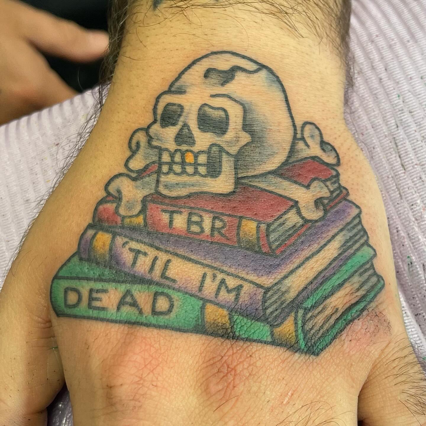 Skull and books American traditional tattoo on the forearm by Sue Garcia