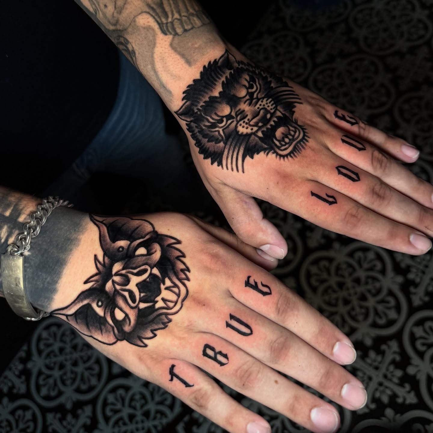 Lion and wolf heads American traditional tattoo on the hand by @ryanpereztattoo