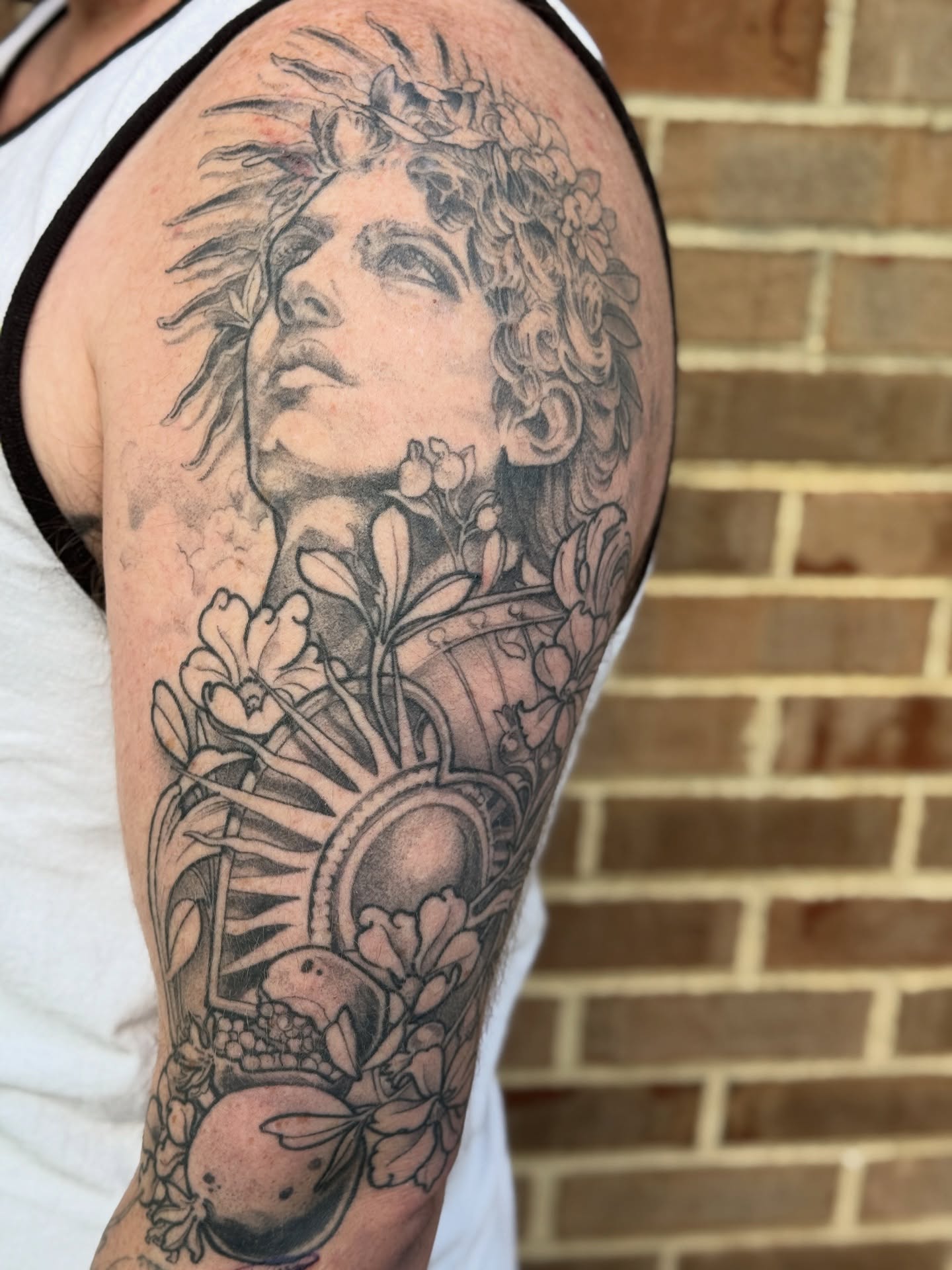 Mythical figure with flowers realism tattoo on the forearm by Joe Hall
