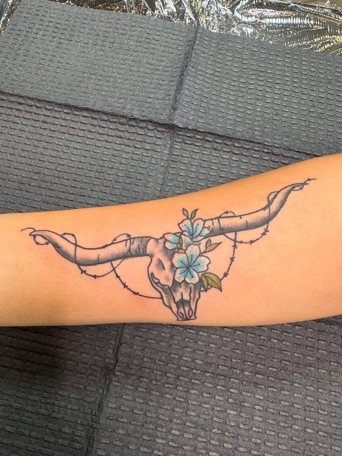 Bull skull with flowers black and grey tattoo on the forearm by spikecitytattoo