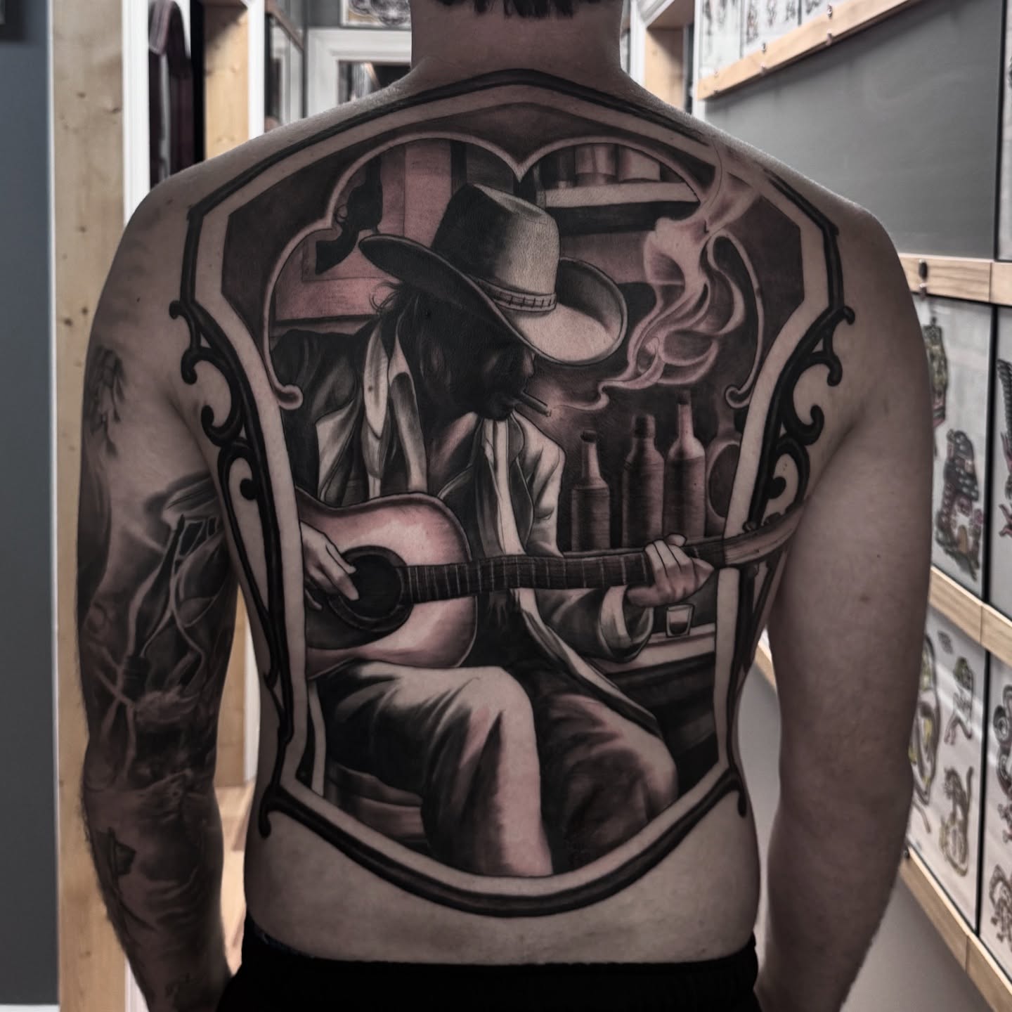 Musician playing guitar realism tattoo on the back by Jake Fujimura