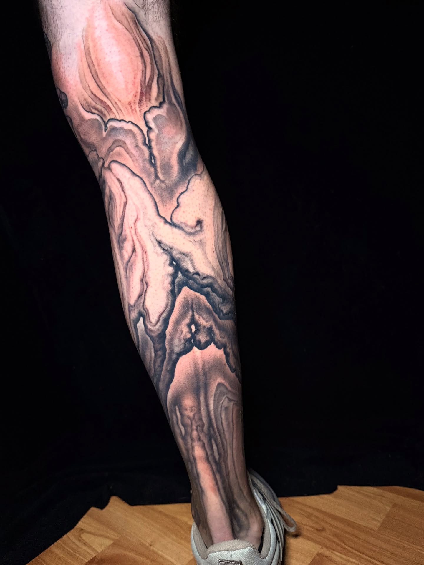 Abstract fluid black and grey tattoo on the calf by Jake Kirk