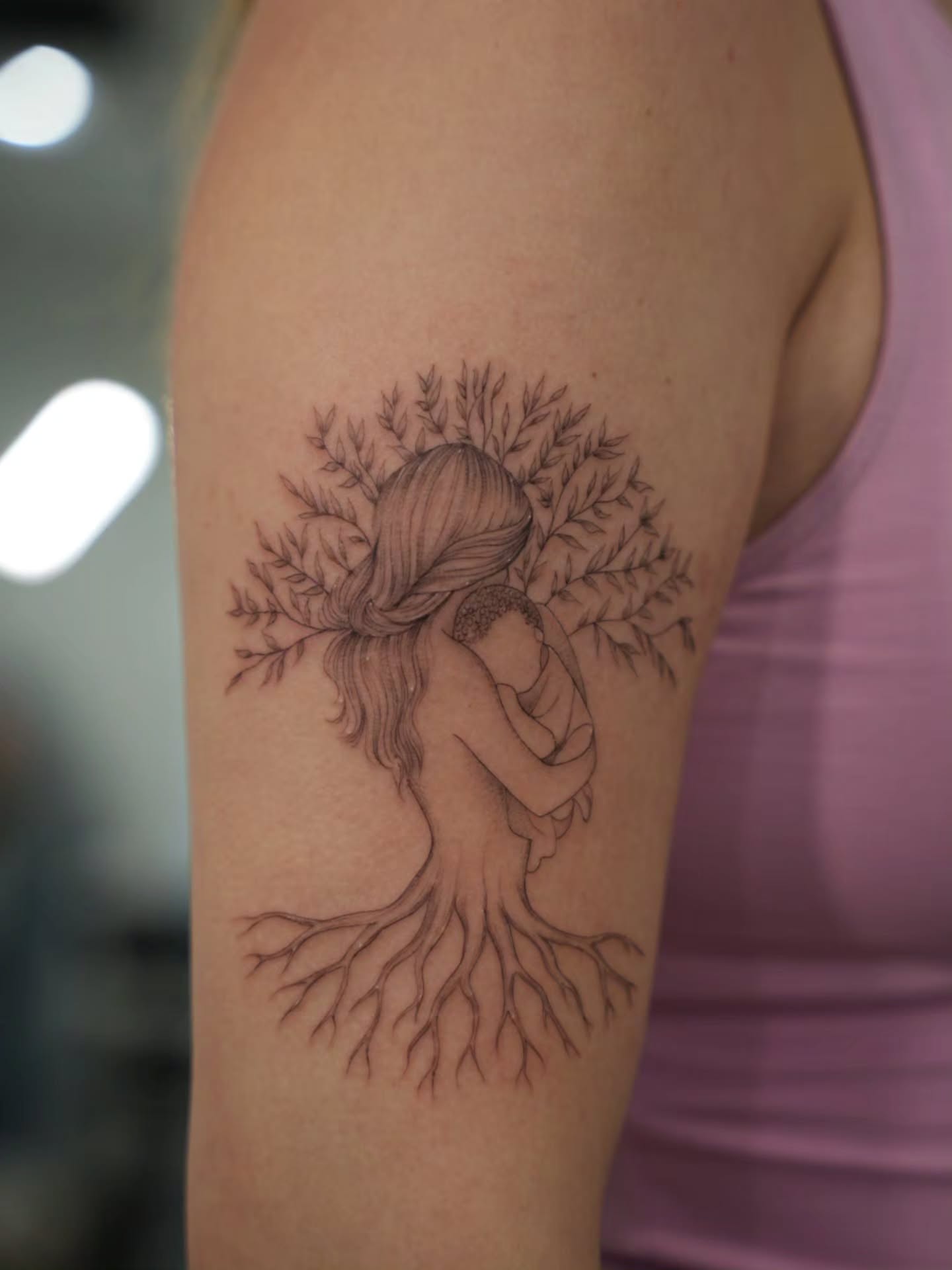 Mother and child black and grey tattoo on the upper arm by Adriano Bassalo