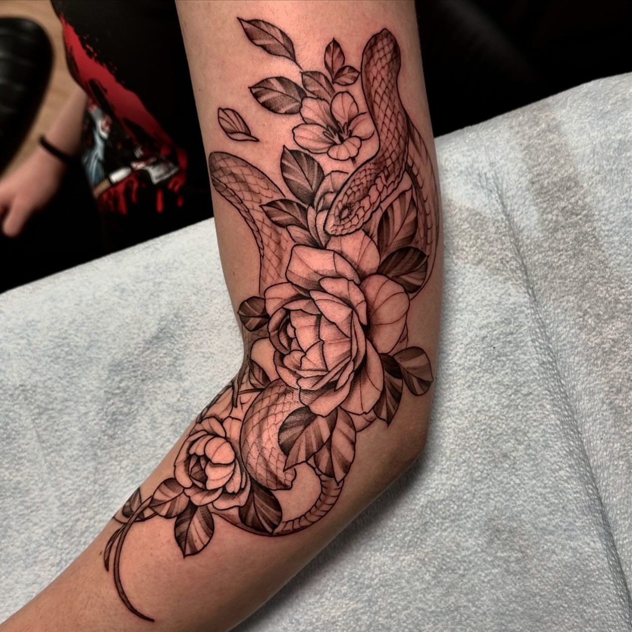 Snake and roses black and grey tattoo on the forearm by Sebastian Livingston