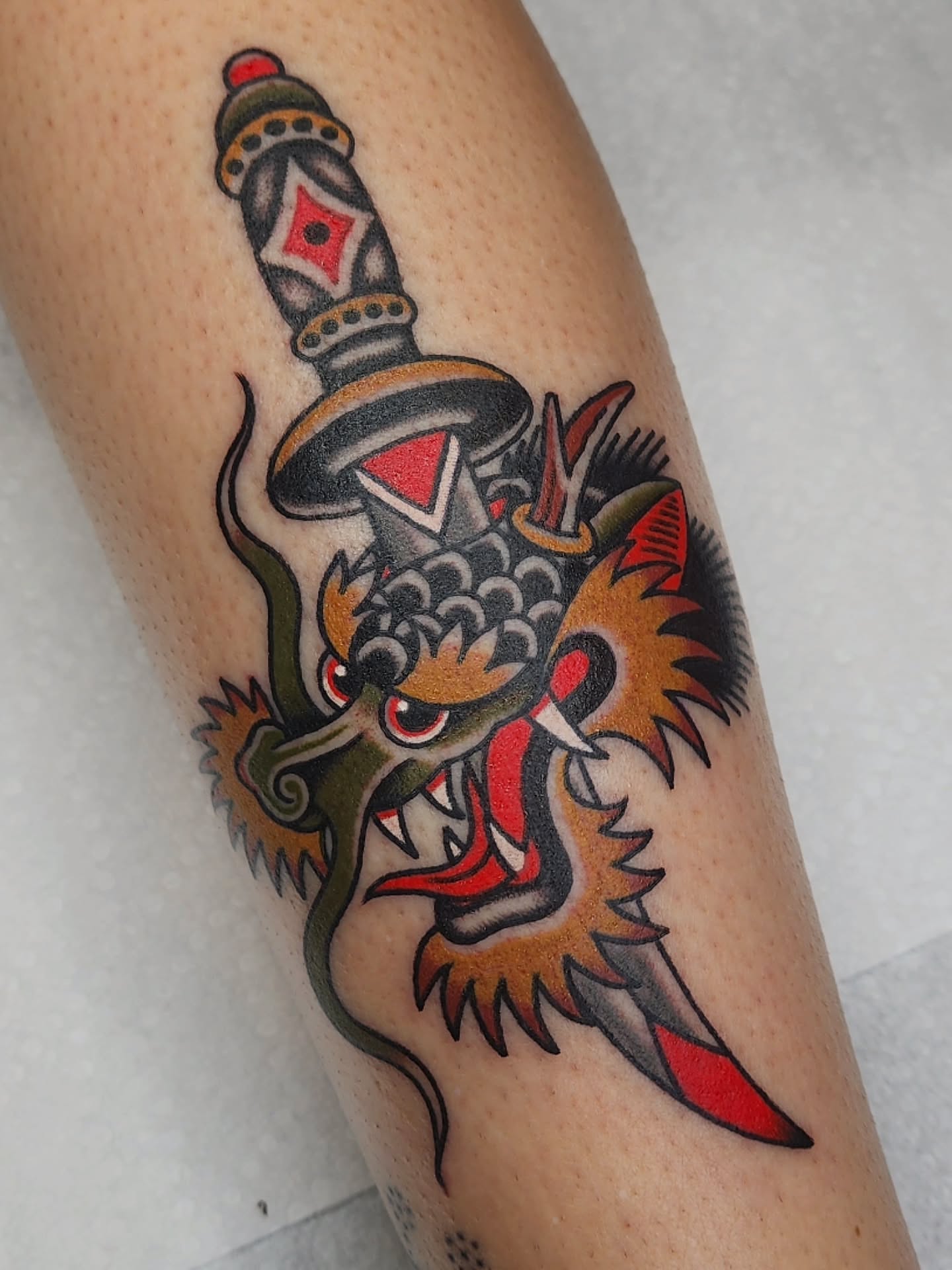 Dragon and dagger American traditional tattoo on the forearm by 𝘈𝘋𝘈𝘔 𝘉𝘈𝘙𝘕𝘌𝘚