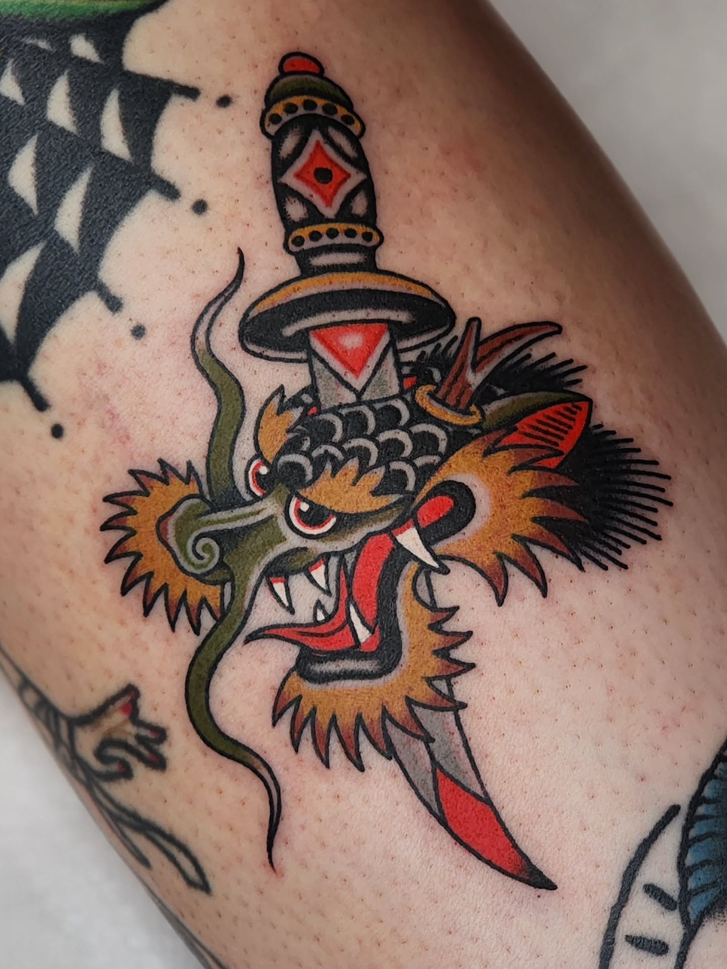 Dragon and dagger American traditional tattoo on the thigh by 𝘈𝘋𝘈𝘔 𝘉𝘈𝘙𝘕𝘌𝘚