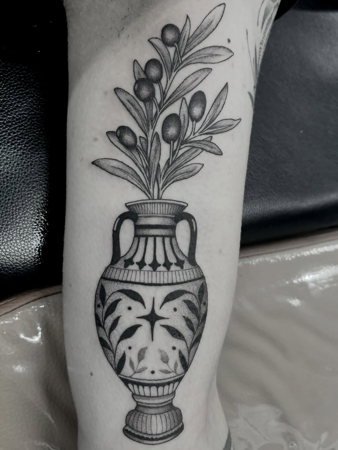 Olive branch in an urn surrealism tattoo on the forearm by Zoe D