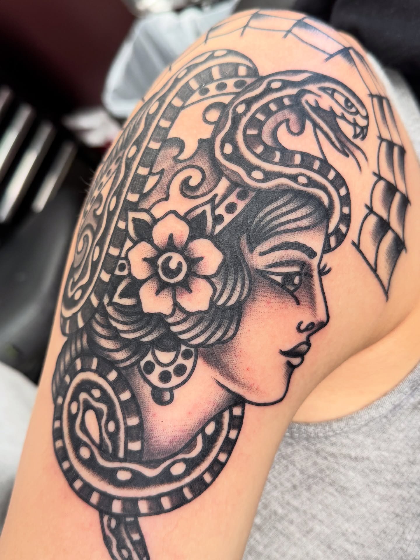 Woman with snake American traditional tattoo on the shoulder by Joey Burdette Tattoos