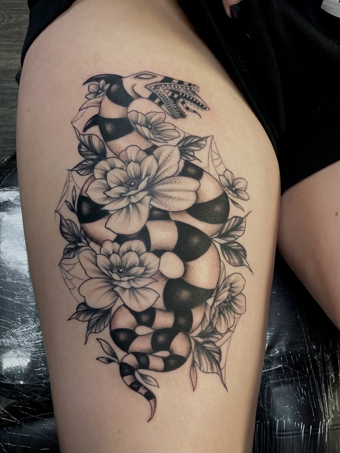 Snake and flowers American traditional tattoo on the thigh by Emma Thompson