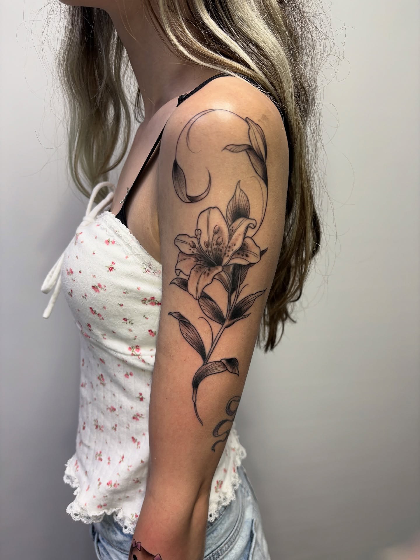 Lily black and grey tattoo on the forearm by Emma Thompson