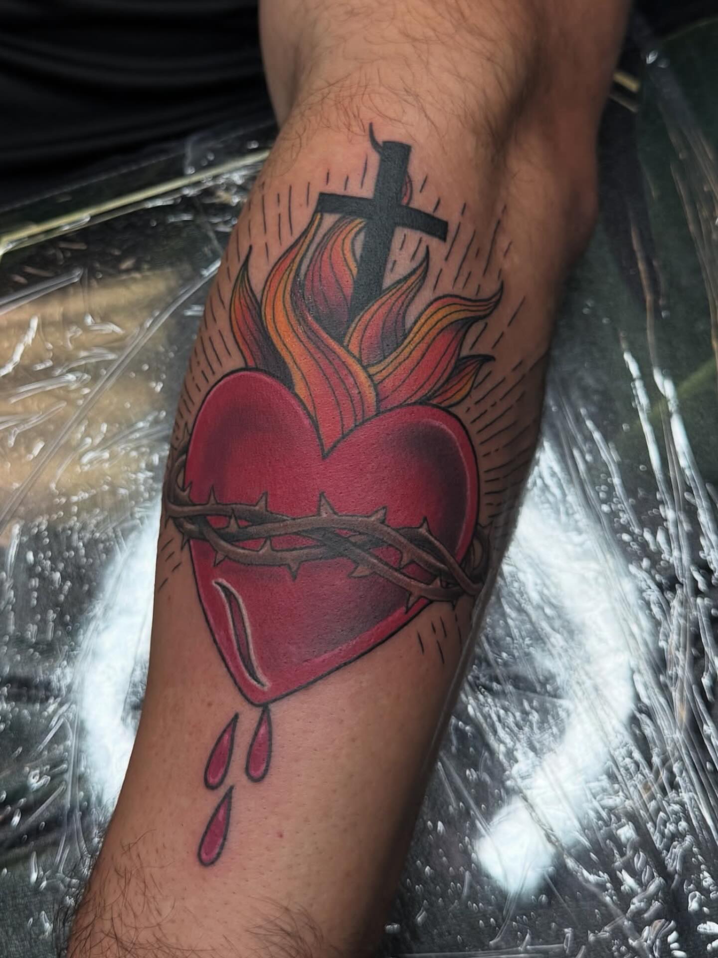 Heart with cross and flames American traditional tattoo on the forearm by Kelsey Kemp