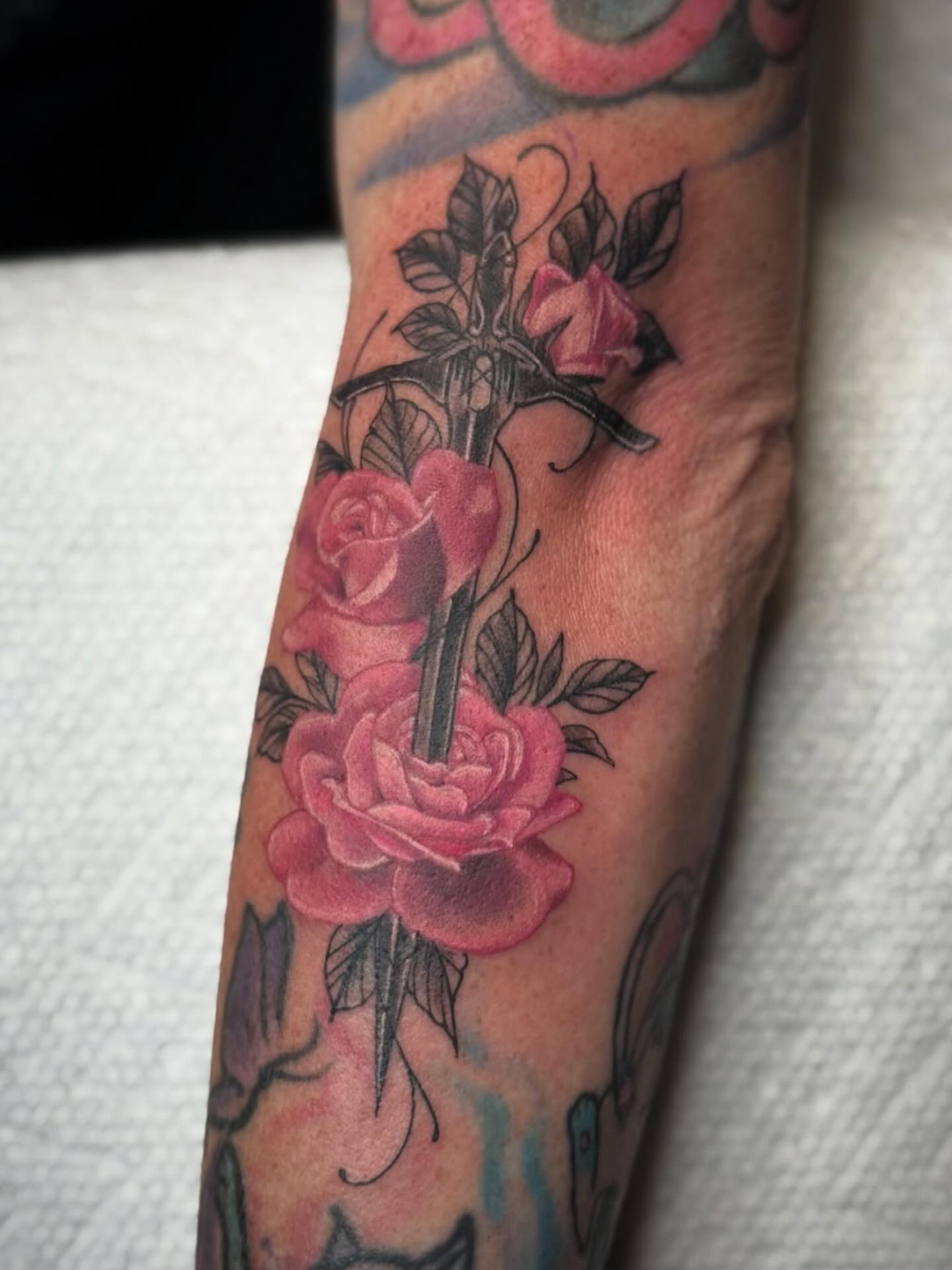 Roses and sword American traditional tattoo on the forearm by Kelsey Kemp