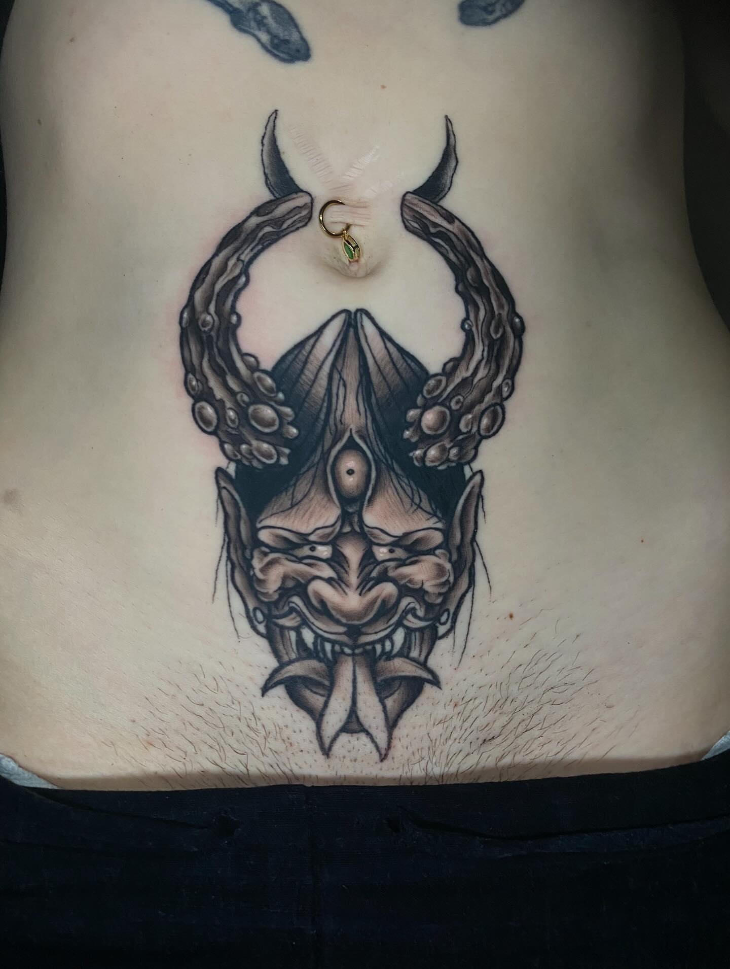 Demon mask black and grey tattoo on the torso by Shelby Warren