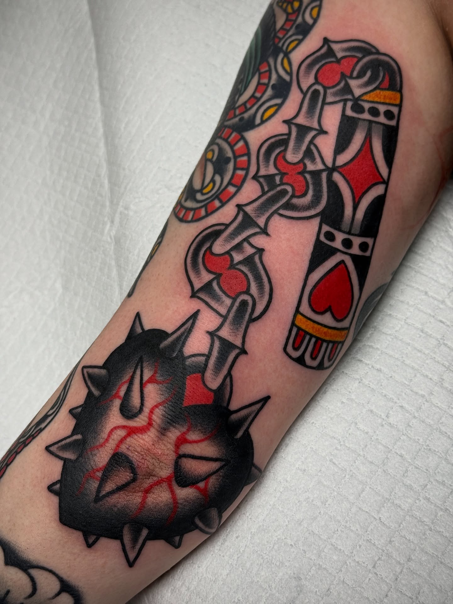 Spiked armor and playing cards American traditional tattoo on the forearm by Jordan Allen