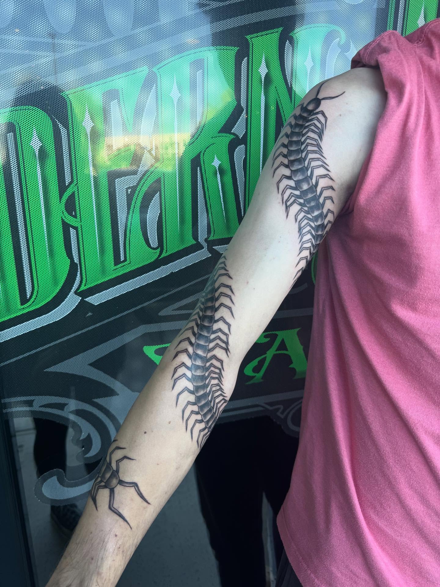 Centipede black and grey tattoo on the upper arm by Jianna