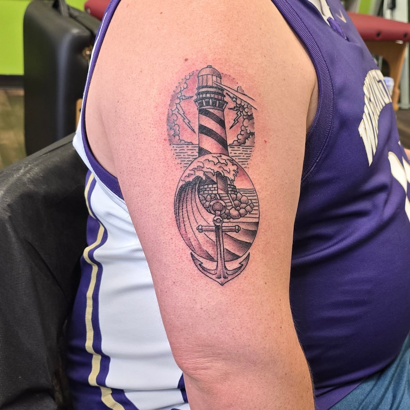 Lighthouse and anchor black and grey tattoo on the upper arm by Steve Atkinson Tattoo Artist