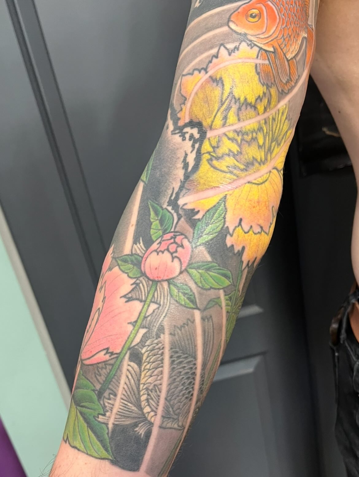 Goldfish and peony American traditional tattoo on the forearm by Miles Maniaci, Chicago, Illinois