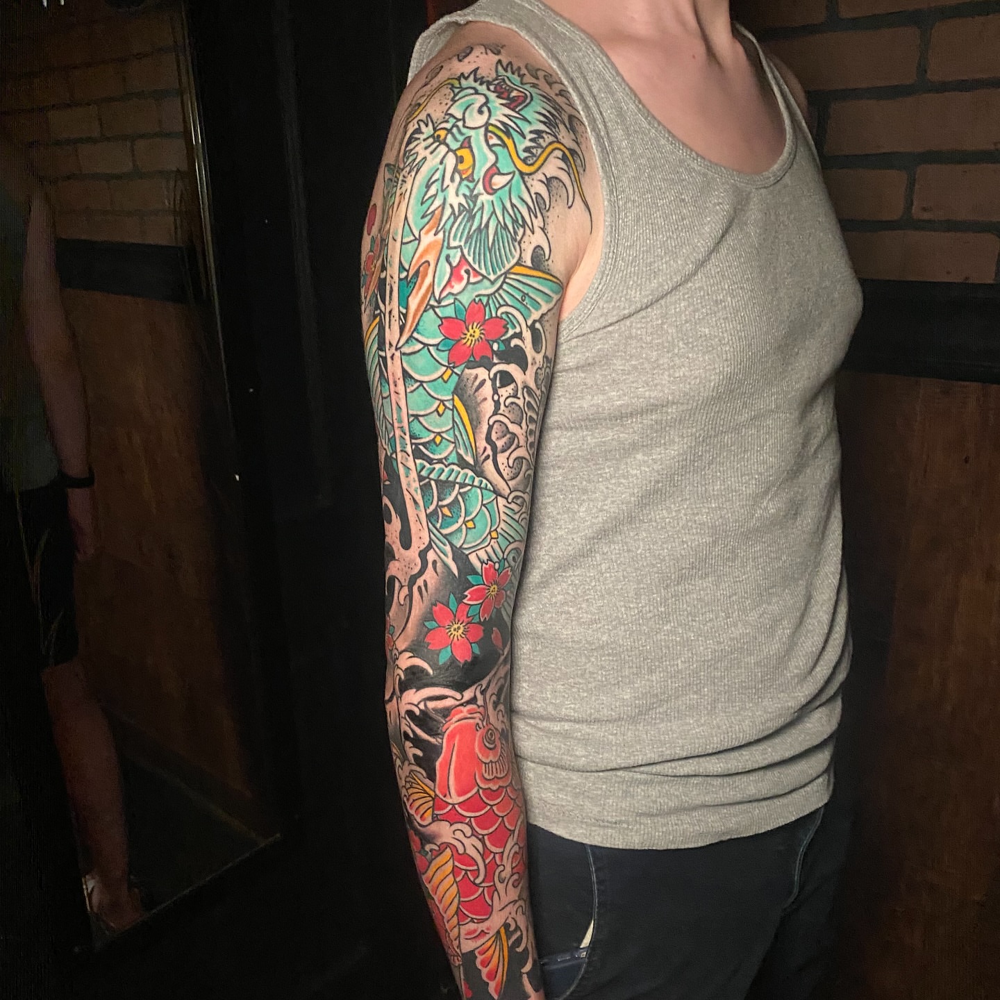 Dragon and flowers American traditional tattoo on the upper arm by Nick Weaver