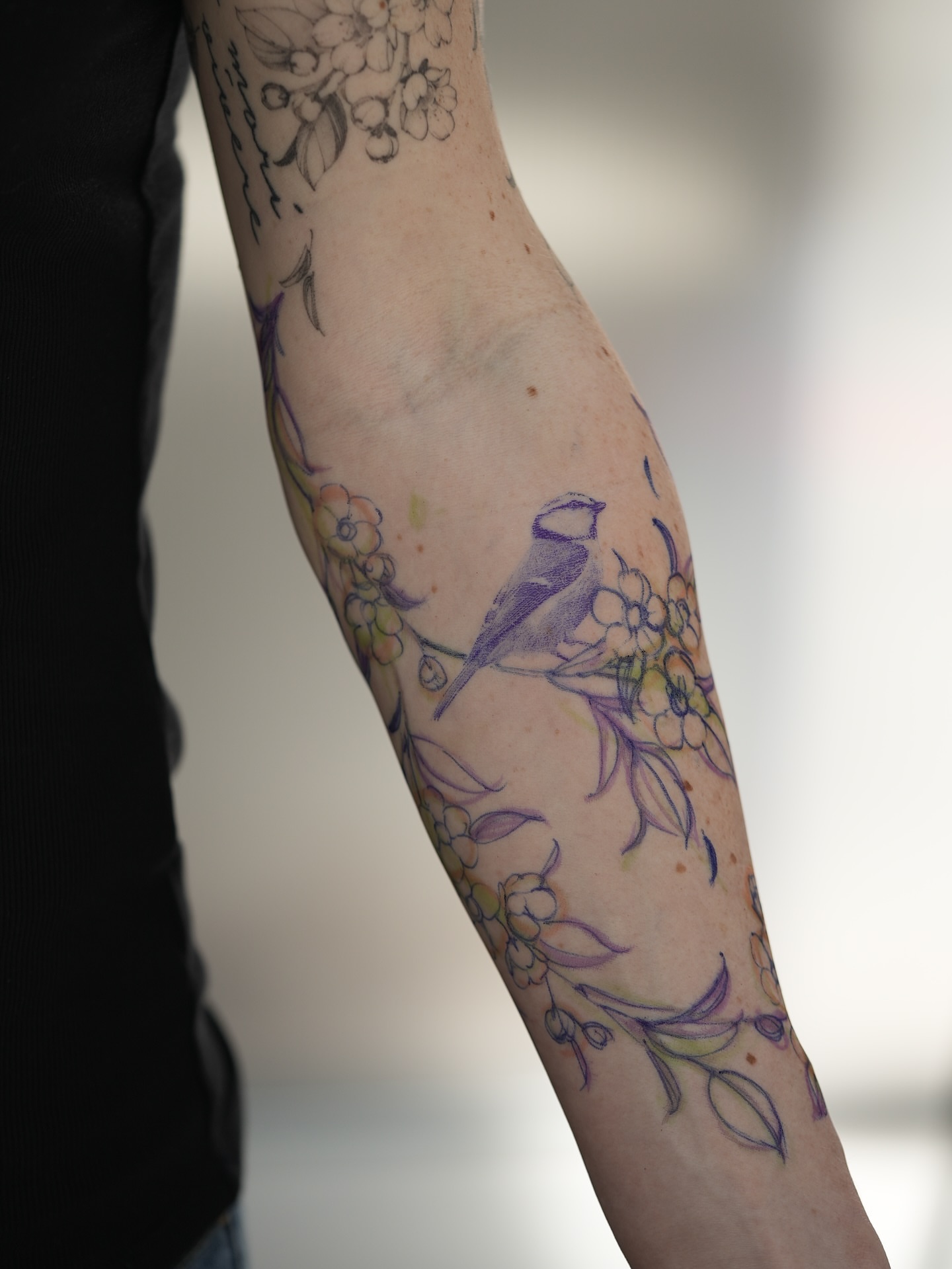 Bird and flowers watercolor tattoo on the forearm by Mary Shekh