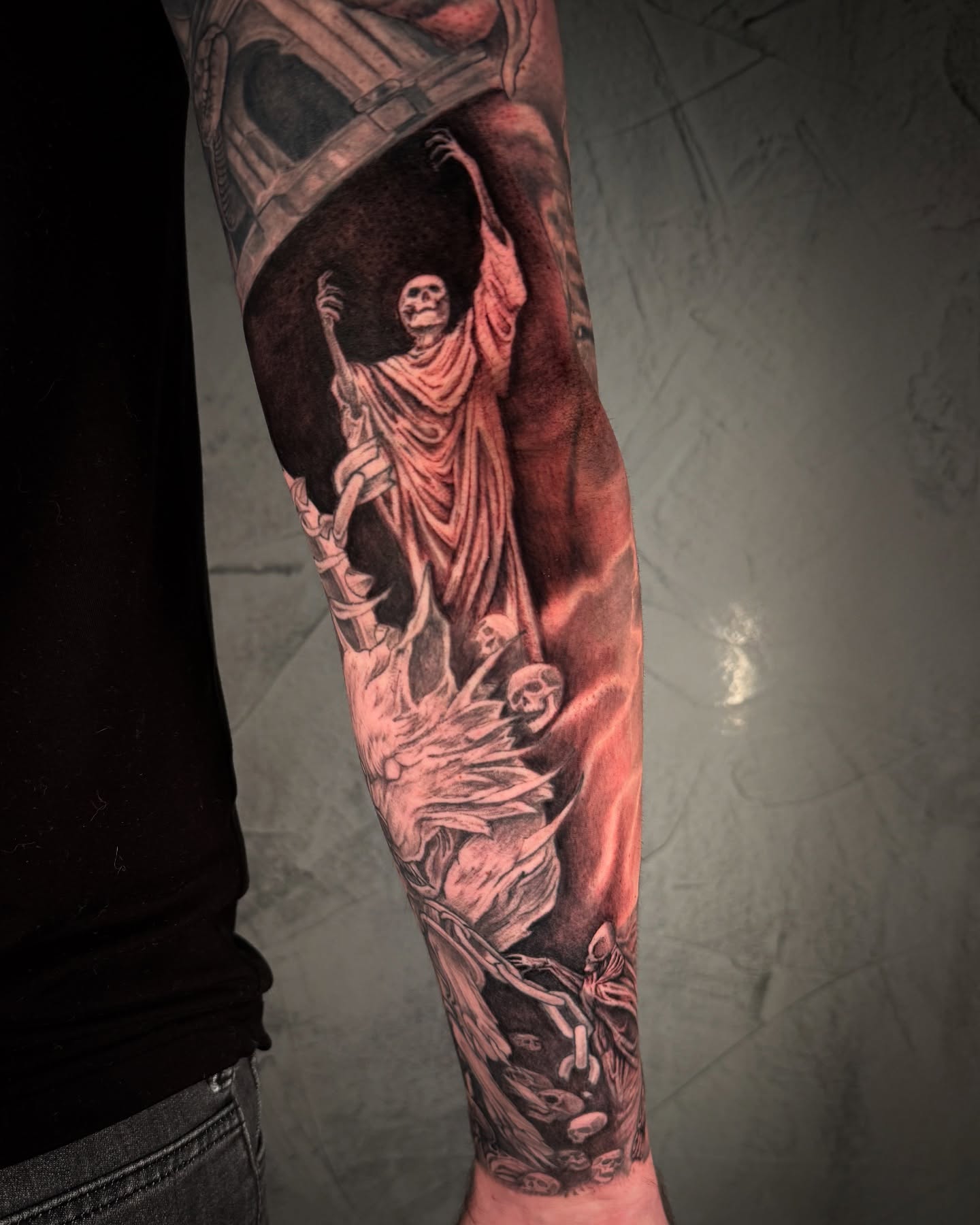 Skeletons and draped figure realism tattoo on the forearm by Ethan Lund
