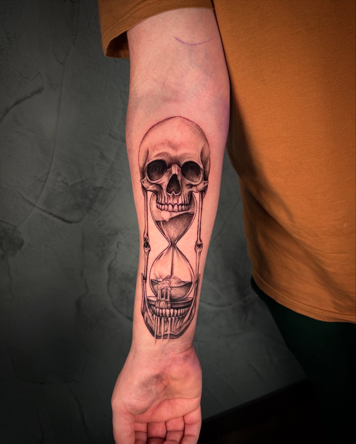 Hourglass and skull realism tattoo on the forearm by Ethan Lund