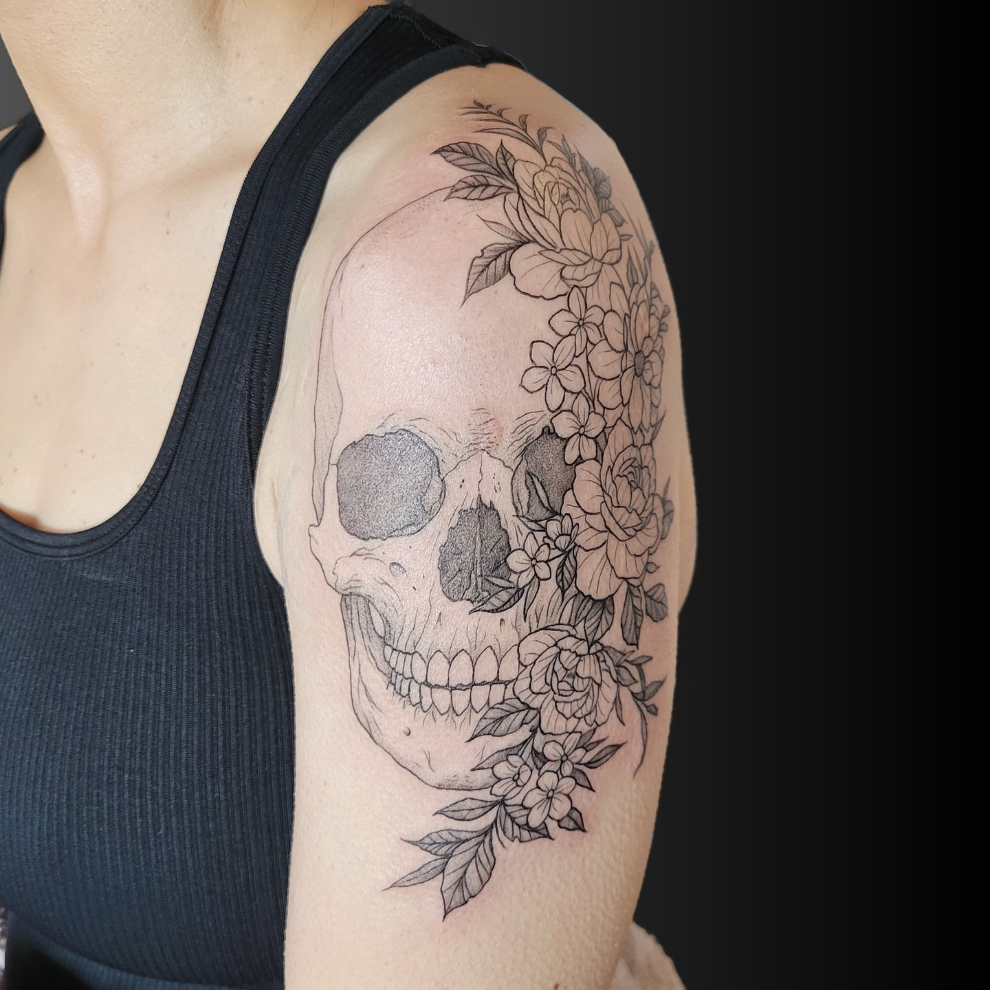 Skull with flowers realism tattoo on the shoulder by Arick Reese