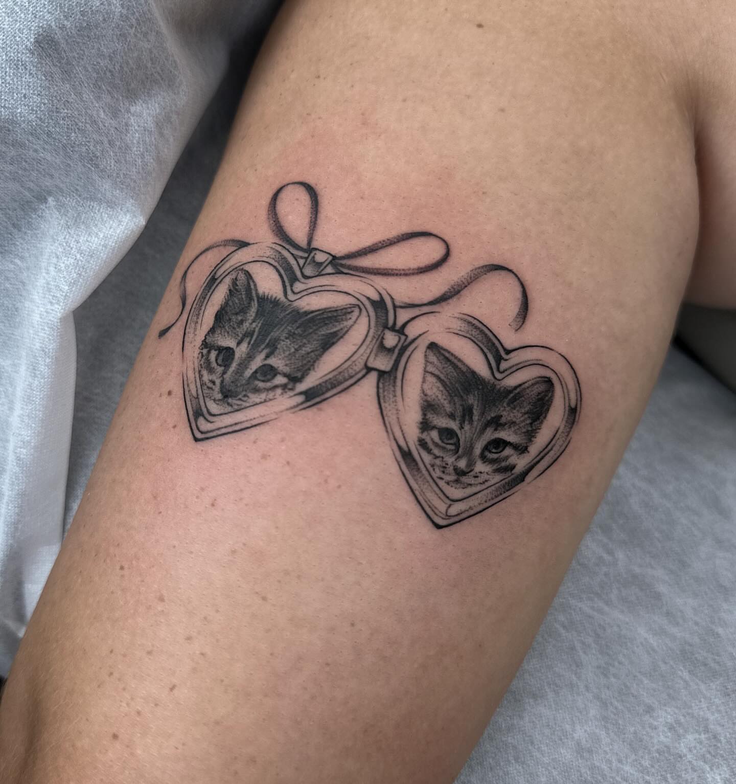 Heart-shaped locket with cat realism tattoo on the forearm by Maggie Angulo