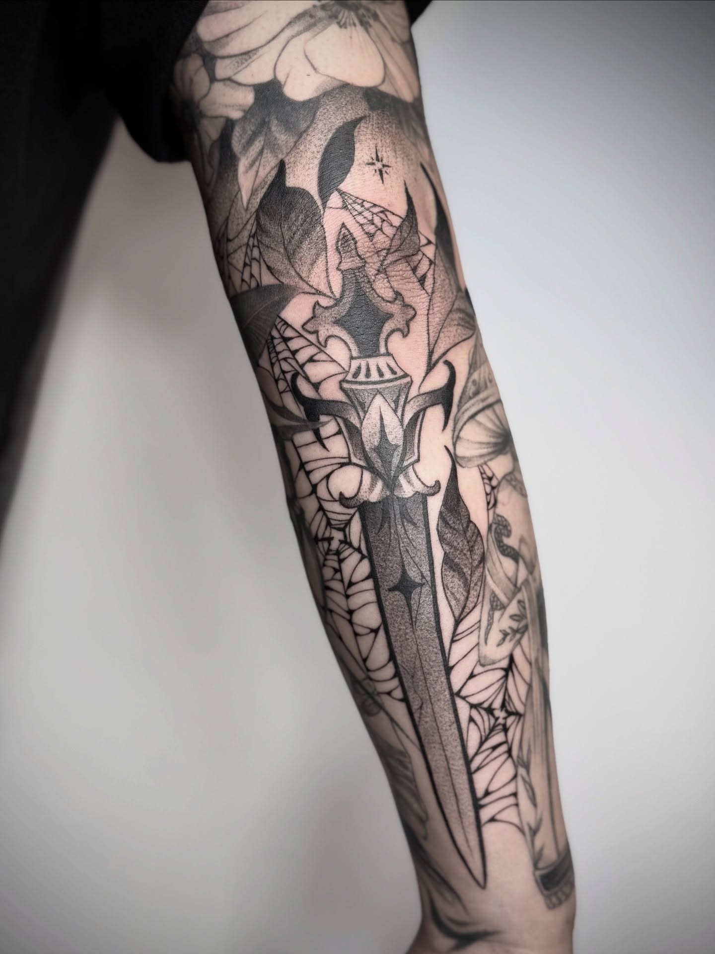 Sword and floral geometric tattoo on the forearm by Abrianna