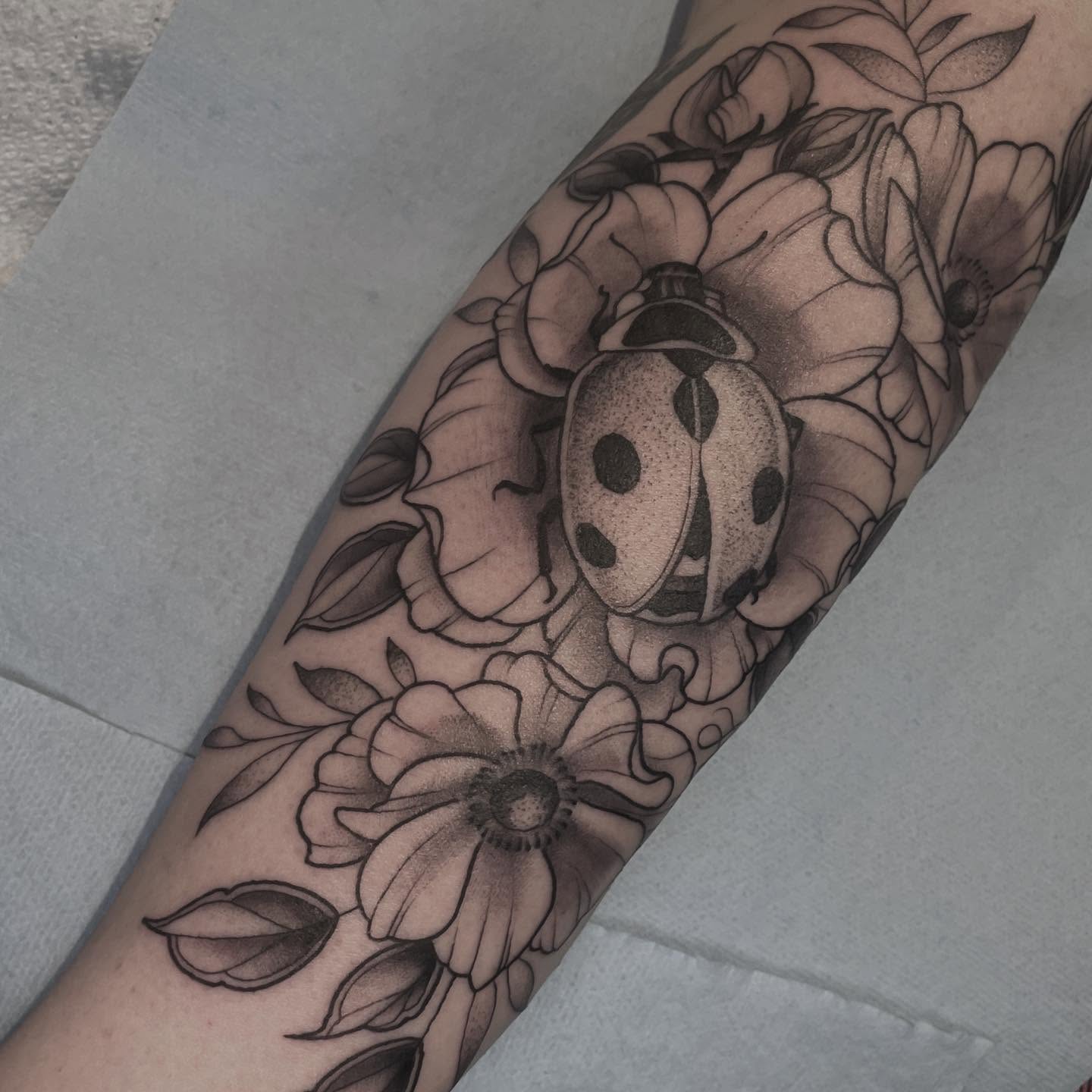 Ladybug and flowers black and grey tattoo on the forearm by Amanda Marie, Edmonds, Washington