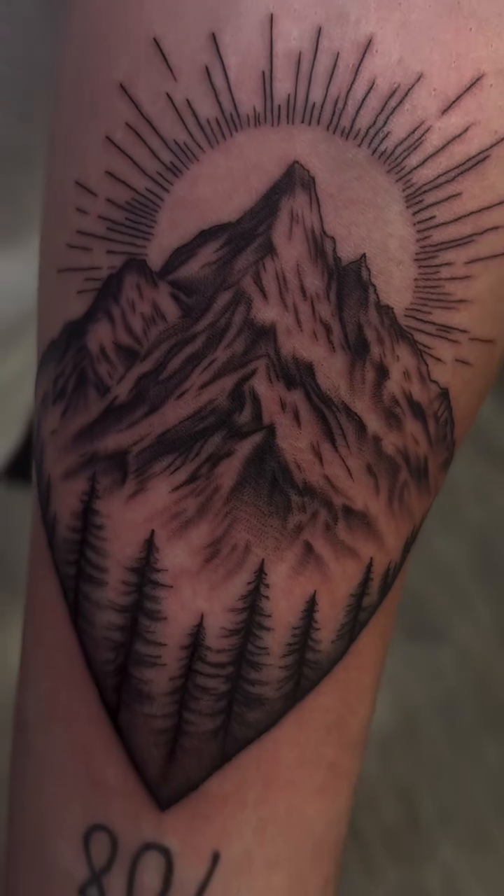 Mountain landscape with sun and trees realism tattoo by Ryan Walker