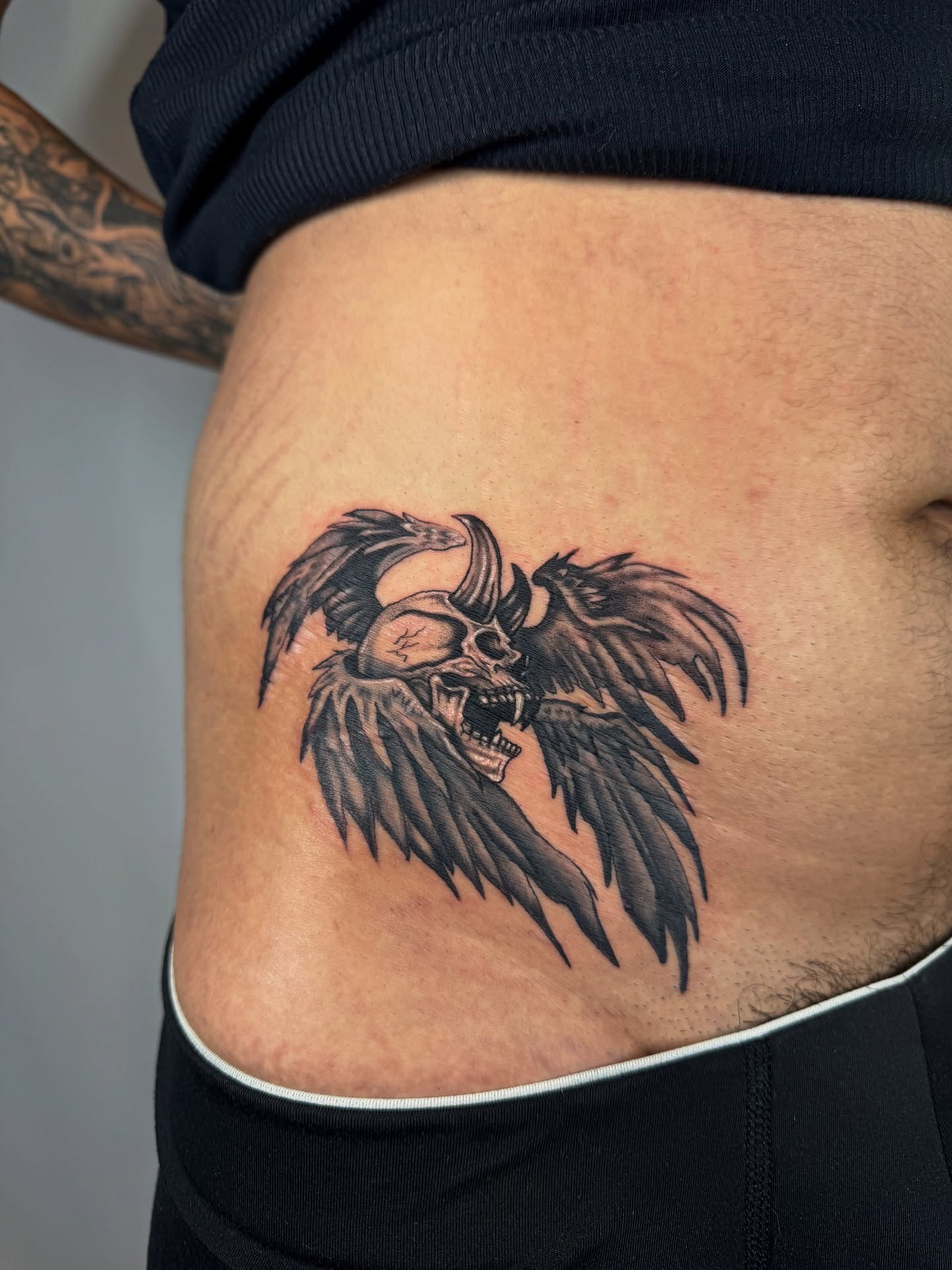 Skull with wings black and grey tattoo on the ribs by Franky A Bonifacio, Seattle, Washington