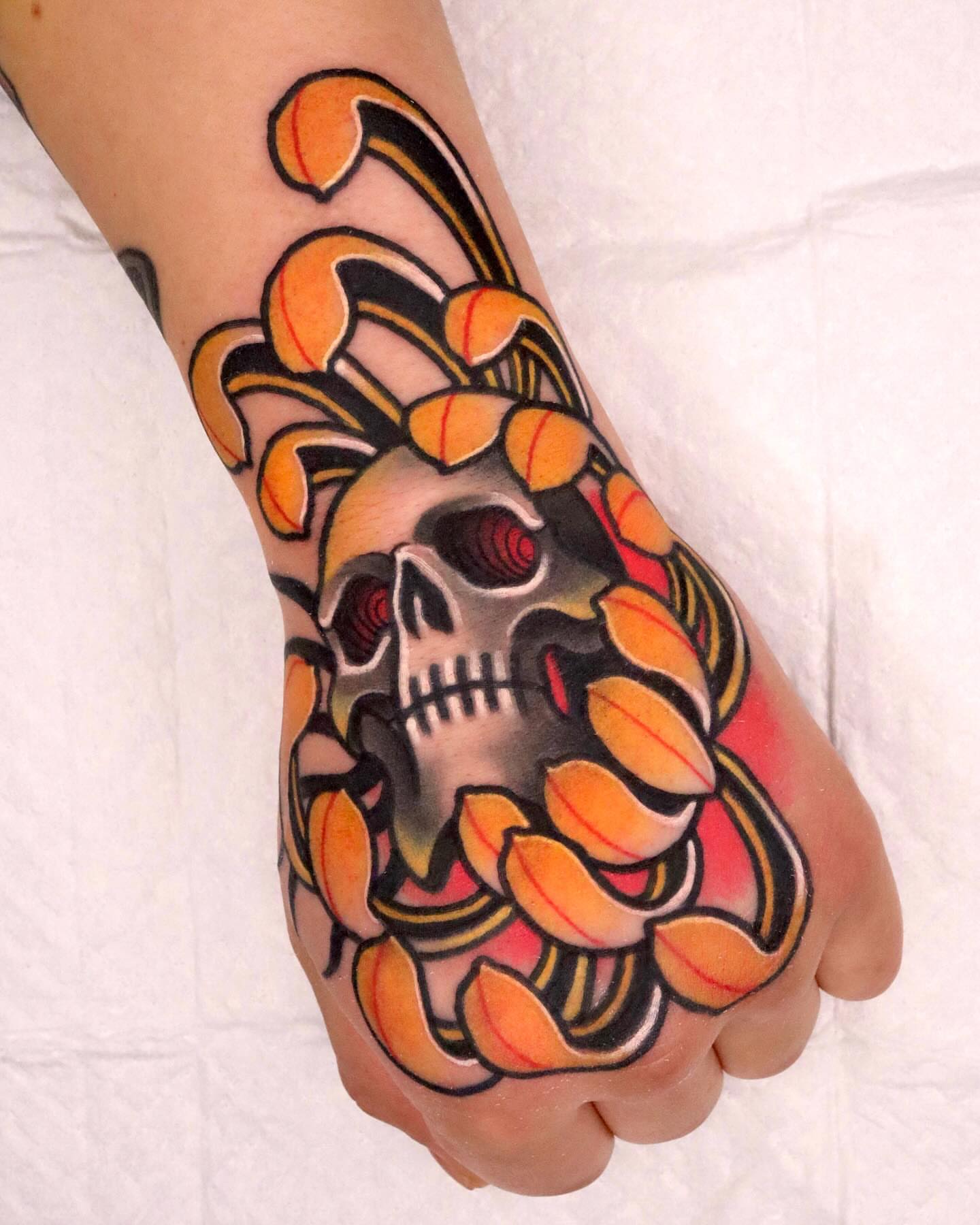 Skull and floral American traditional tattoo on the hand by 부산타투