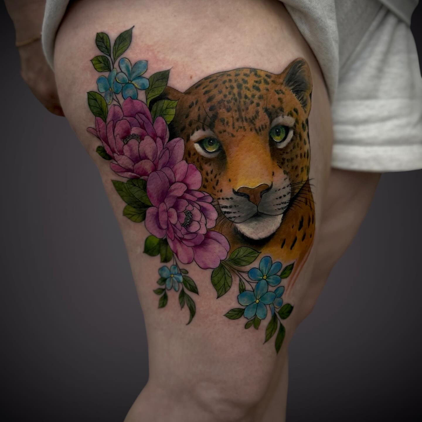 Jaguar with flowers realism tattoo on the thigh by Mitsuko Ching