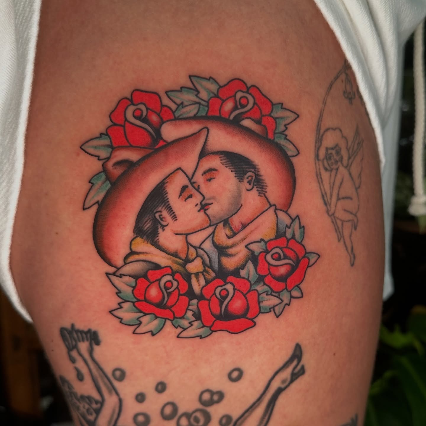 Couple kissing surrounded by roses American traditional tattoo on the thigh by Max Peterson