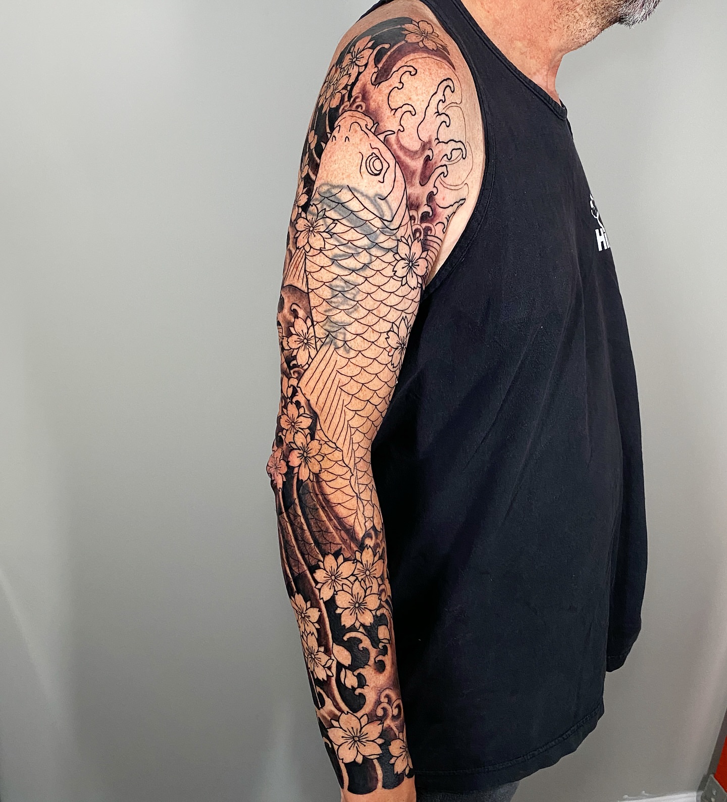 Koi fish and cherry blossoms japanese irezumi tattoo on the upper arm by Eric James, Phoenix, Arizona