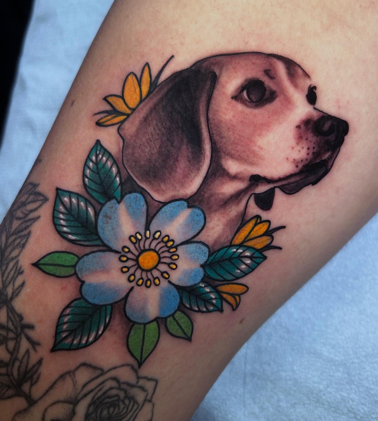 Dog with flowers American traditional tattoo on the forearm by Katie Dexter, Des Moines, Iowa