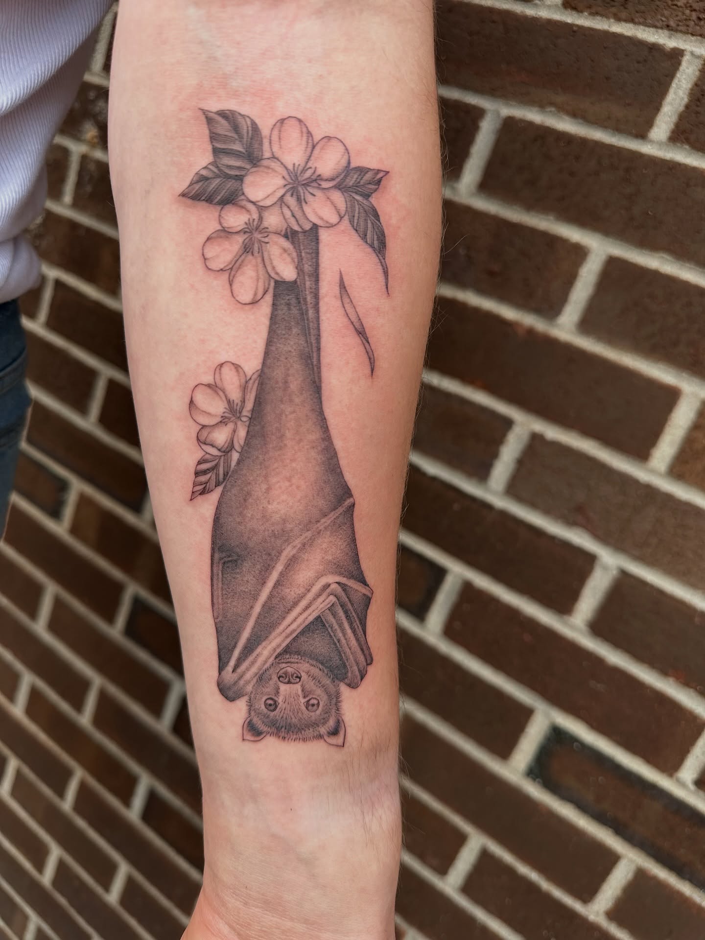Bat and flowers black and grey tattoo on the forearm by Hail Chaney, Somerville, Massachusetts