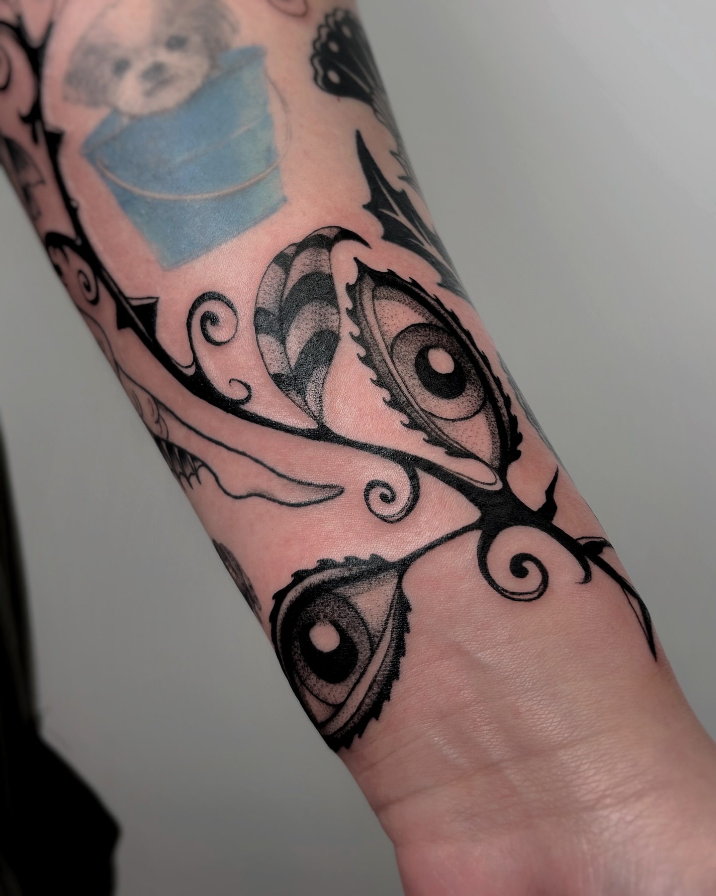 Eyes and floral dotwork tattoo on the forearm by Kuya, Berkeley, California