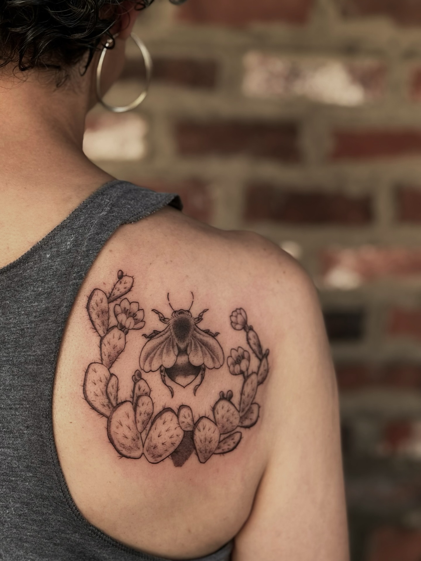 Prickly pear cactus and bee black and grey tattoo on the shoulder by Virginia 🥀Neo Traditional