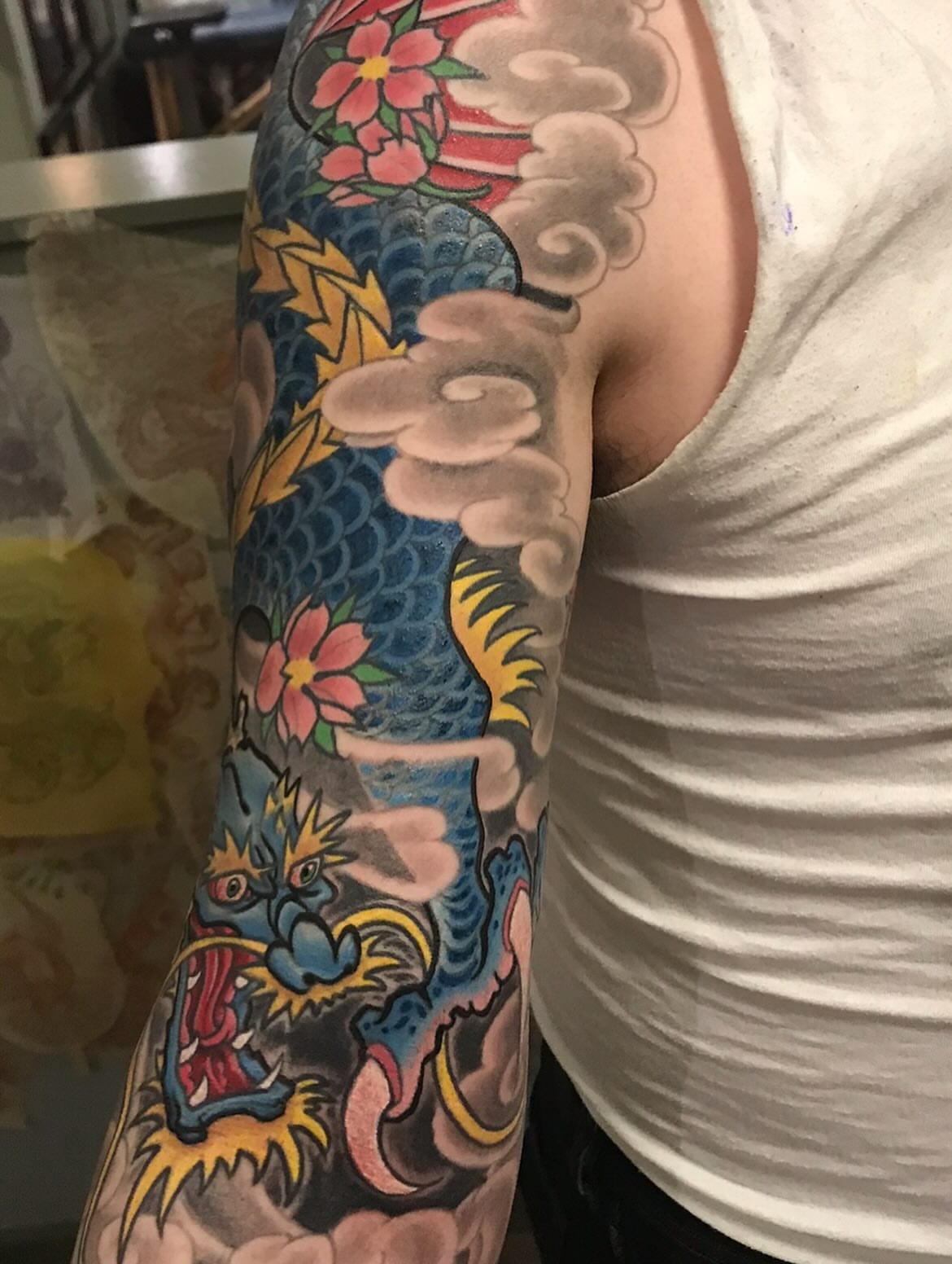 Dragon and flowers American traditional tattoo on the upper arm by Miles Maniaci, Chicago, Illinois