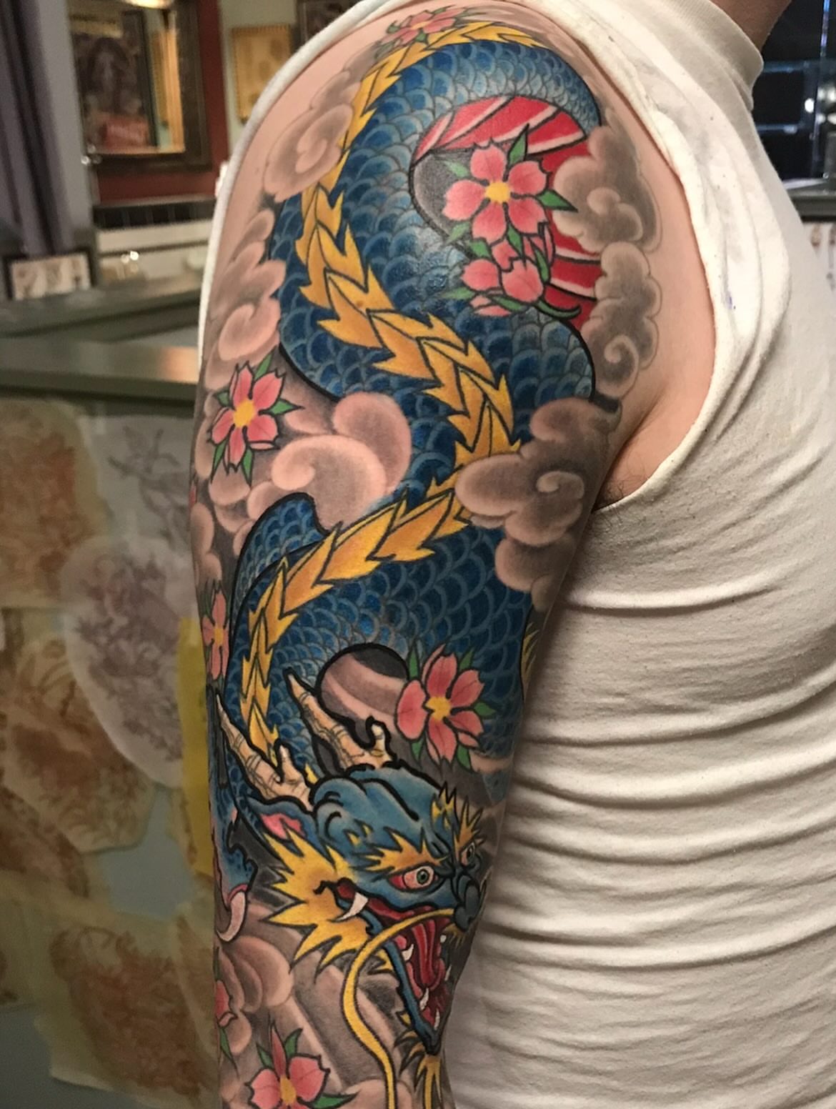 Dragon and flowers American traditional tattoo on the upper arm by Miles Maniaci, Chicago, Illinois