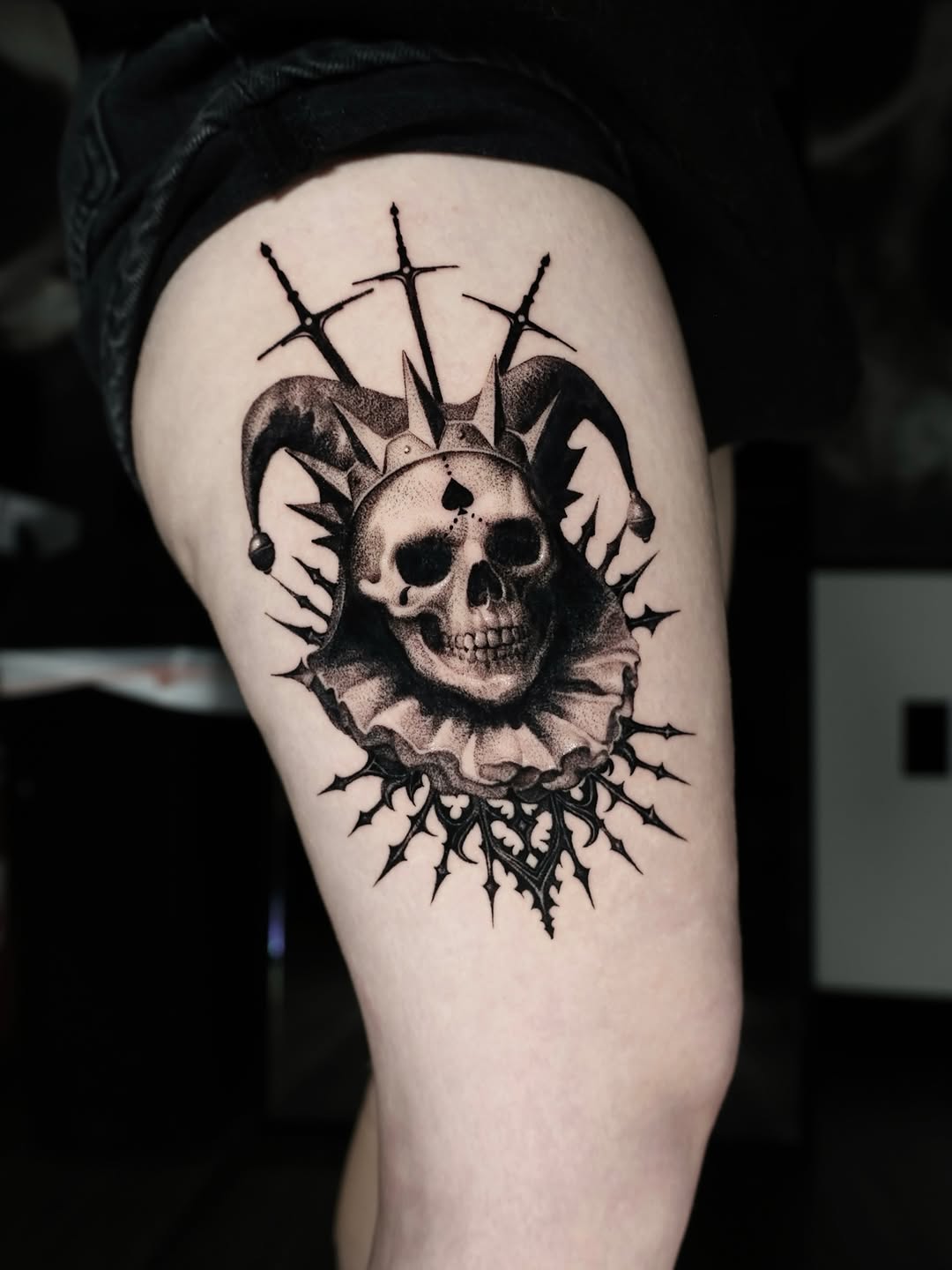 Jester skull with swords dark art tattoo on the thigh by Anna Chernova, San Francisco, California