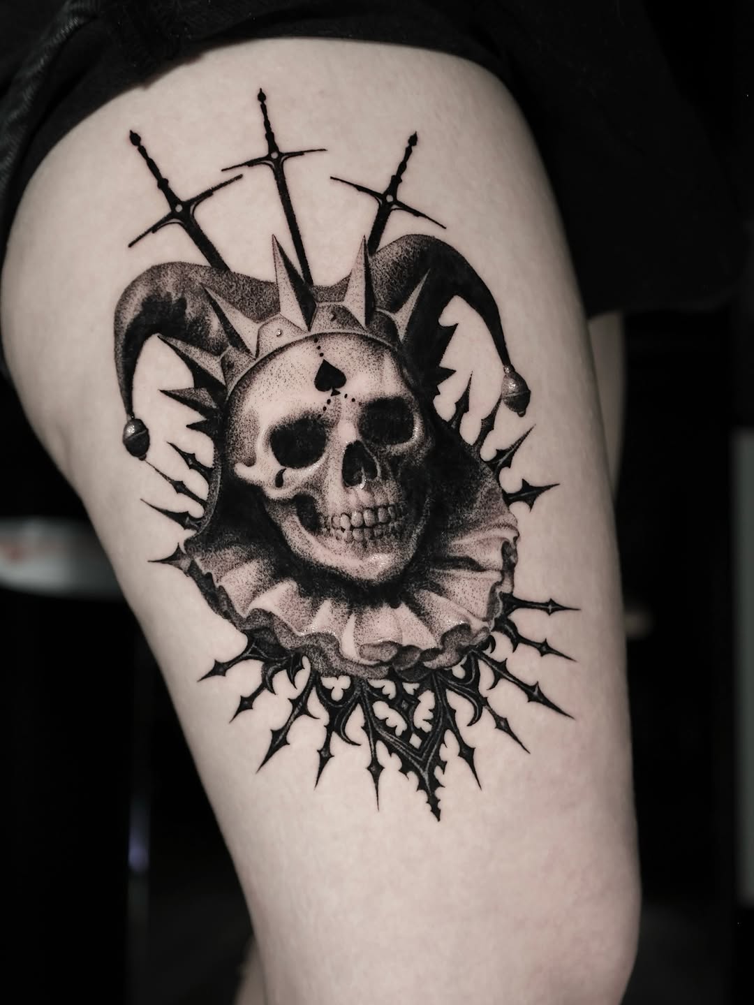 Jester skull with swords dark art tattoo on the thigh by Anna Chernova, San Francisco, California