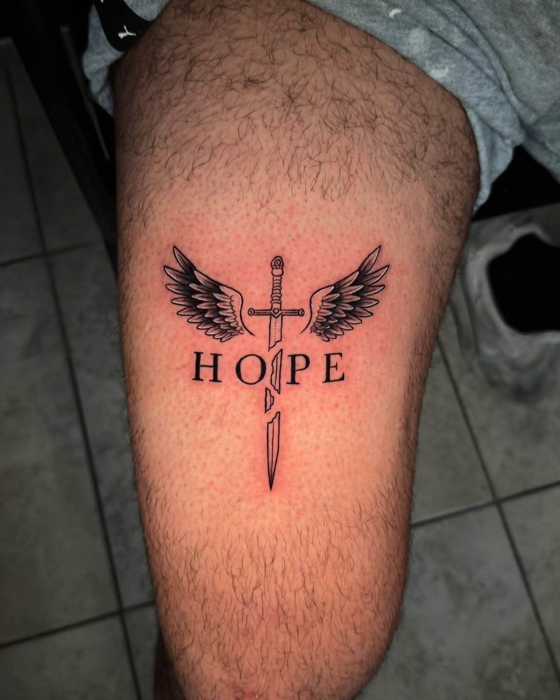 Sword and wings black and grey tattoo on the thigh by Ayala Jose