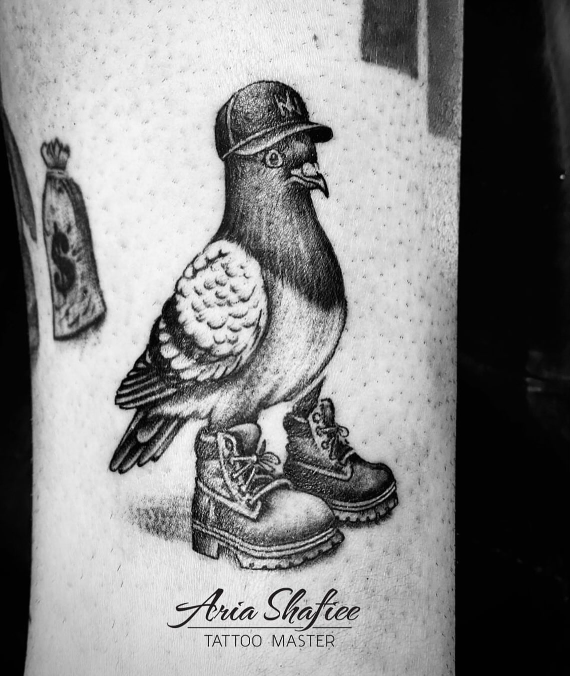 Pigeon wearing cap and boots realism tattoo on the forearm by Aria Shafiee