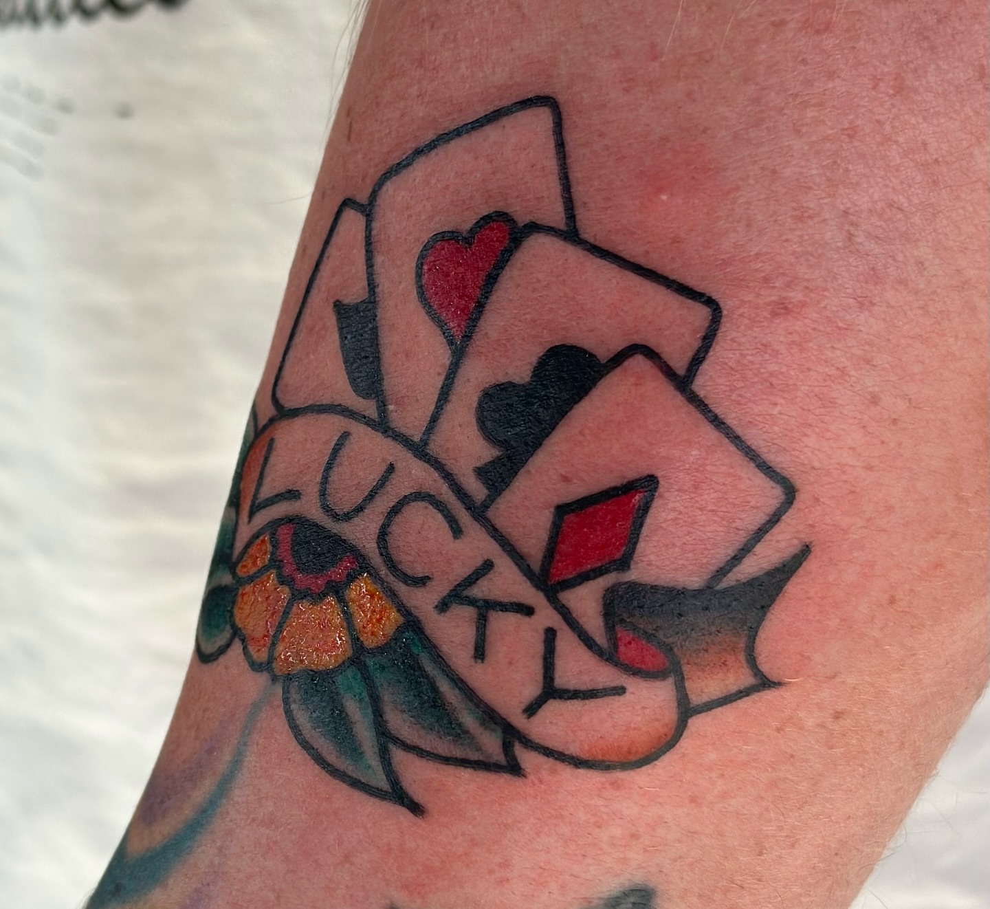 Playing cards and 'LUCKY' American traditional tattoo on the forearm by Hayley Hendrick