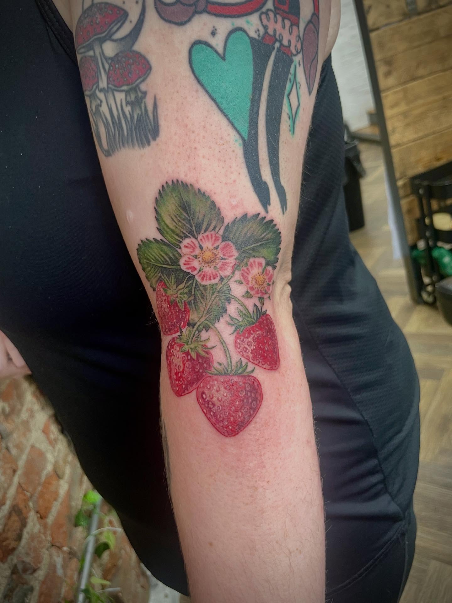 Strawberries and leaves realism tattoo on the forearm by Grace derby tattooist, Derby